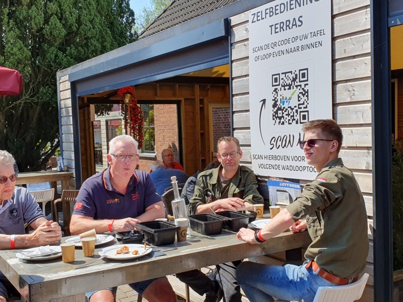 Chauffeurs en bijrijders genieten in de zon van patat en kibbeling.